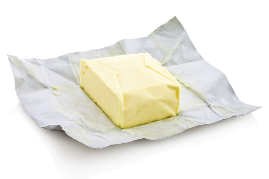 Unpacked block of butter from the shop, placed on embossed foil paper. Isolated on white background with shadow reflection. With clipping path. With vector path. Piece of butter from supermarket.
