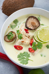 Close-up of thai traditional tom kha or tom kha gai soup in a white bowl, vertical shot, selective focus