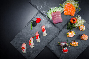 Sushi, traditional Japanese cuisine. Several delicious sushi on the decorated plate, black background. Group of sushi, Urakami, Nigori, Sushi jow, sashimi, tekamaki, etc ...