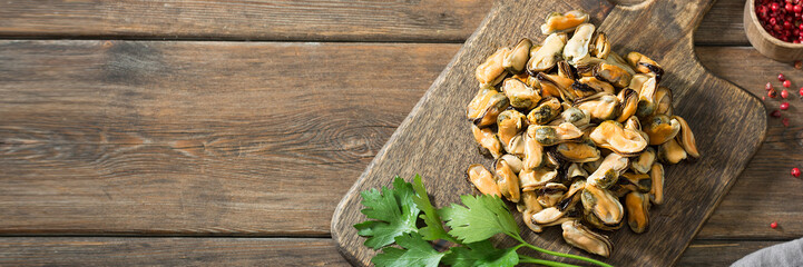 Mussel meat on a wooden Board on a wooden table. Rustic style. Top view with space for text. Banner