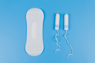 Sanitary pad and tampons on blue background. Top view