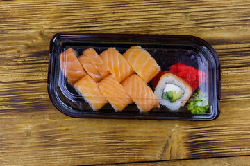 Sushi rolls Philadelphia in plastic box on wooden table. Top view. Sushi for take away or delivery of sushi in plastic container