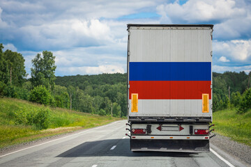 A  truck with the national flag of Russia depicted on the back door carries goods to another...