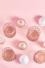 geometric pattern of the candlesticks and candles of copper-colored on a pink background. flat lay, top view, vertical frame