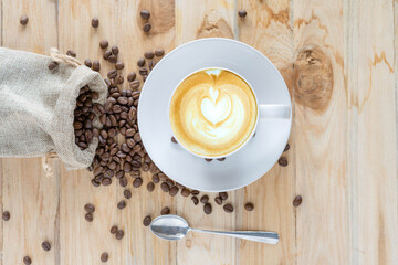 Hot Coffee Latte Art on a wooden table with raw coffee beans soft focus, And free space.