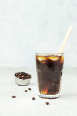 Espresso tonic, refreshment summer drink with tonic water, coffee and ice cubes, light grey concrete background. Trendy coffee drink.