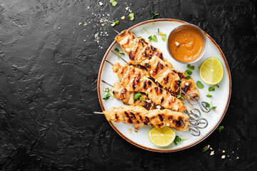 Grilled chicken satay skewers with peanut butter sauce.