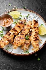 Grilled chicken satay skewers with peanut butter sauce.