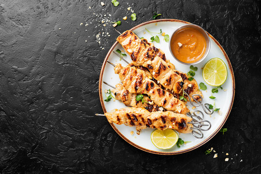 Grilled chicken satay skewers with peanut butter sauce.