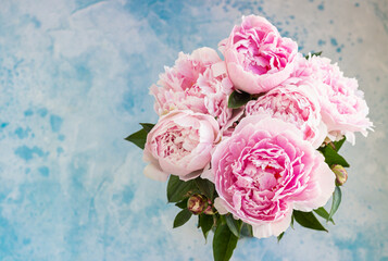 Bouquet of beautiful pink peonies, blue concrete background. Top view. Flowers texture. Copy space.