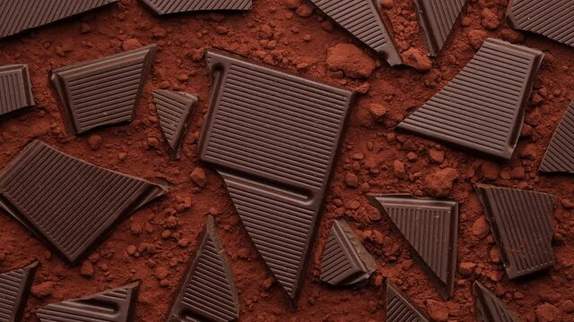 broken chocolate bar and cocoa powder rotating, top view