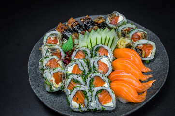 Sushi, traditional Japanese cuisine. Several delicious sushi on the decorated plate, black background. Group of sushi, Urakami, Nigori, Sushi jow, sashimi, tekamaki, etc ...