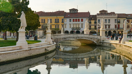 Fototapeta na wymiar PADUA, ITALY - OCTOBER, 2017: Piazza Prato della Valle on Santa Giustina abbey. Prato della Valle elliptical square, surrounded by a small canal and bordered by two rings of statues.