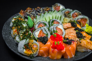 Sushi, traditional Japanese cuisine. Several delicious sushi on the decorated plate, black background. Group of sushi, Urakami, Nigori, Sushi jow, sashimi, tekamaki, etc ...