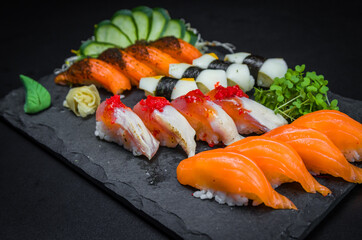 Sushi, traditional Japanese cuisine. Several delicious sushi on the decorated plate, black background. Group of sushi, Urakami, Nigori, Sushi jow, sashimi, tekamaki, etc ...