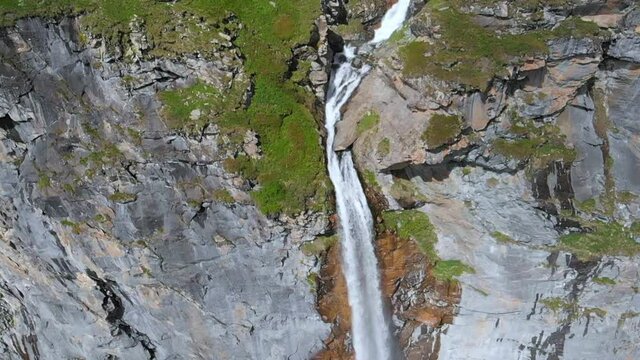 Aerial slow motion: drone flying over scenic high waterfall, mountain stream falling from tall rocky cliff on the italian Alps. Pis waterfall near Torino, Piedmont, Italy