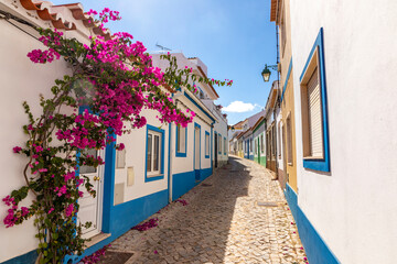 small road in the former fisher village of Ferragudo at the Algarve area with blooming bougainvillea