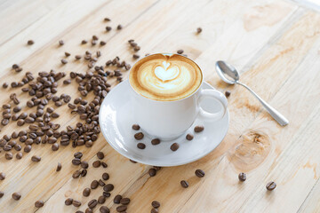 Hot Coffee Latte Art on a wooden table with raw coffee beans soft focus, And free space.