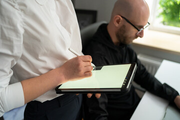 A woman working with color spectrum on a digital tablet while her work colleague working in parallel with laptop in the office. Joint project