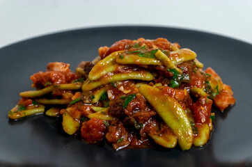 Italian pasta with tomatoes on dark plate