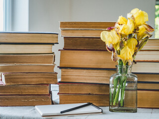 Stack of vintage books and a bouquet of beautiful flowers. Close-up, isolated background. Studio photo. Learning and Education Concept