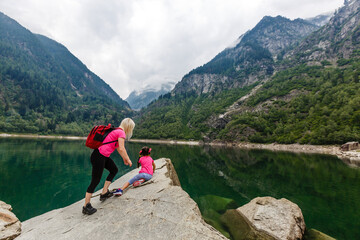 mother and daughter walking in the mountains near lake italy