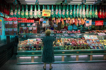 Spain, Barcelona - 2019. A woman in a butcher shop chooses jamon.