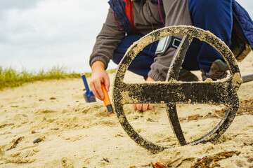 Man with metal detector on sea beach
