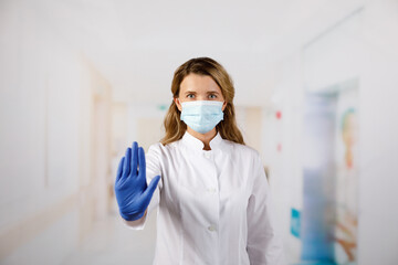 Fototapeta na wymiar Female doctor in face mask showing stop sign with her hand