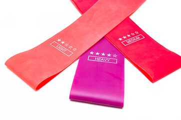 Elastic bands for fitness. Three elastic bands for fitness in close-up on a white background. Erasers lie on the table top and side view. A bunch of rezhinki, twisted into a roll. Elastic bands left 