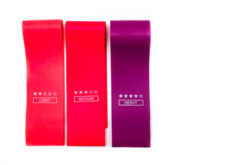 Elastic bands for fitness. Three elastic bands for fitness in close-up on a white background. Erasers lie on the table top and side view. A bunch of rezhinki, twisted into a roll. Elastic bands left 