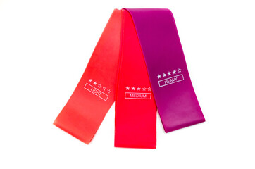 Elastic bands for fitness. Three elastic bands for fitness in close-up on a white background. Erasers lie on the table top and side view. A bunch of rezhinki, twisted into a roll. Elastic bands left 