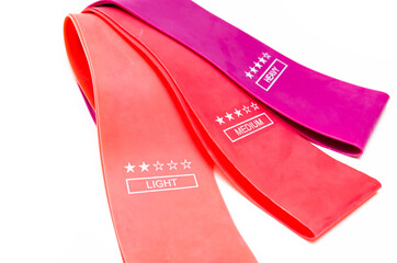 Elastic bands for fitness. Three elastic bands for fitness in close-up on a white background. Erasers lie on the table top and side view. A bunch of rezhinki, twisted into a roll. Elastic bands left 
