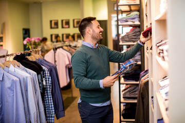 Handsome young man buying clothes in fashion store