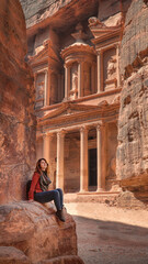 Woman sitting next to the Treasury in the ancient city of Petra, Jordan.
