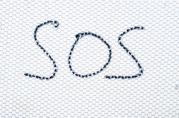 On the blackboard in the form of a honeycomb, SoS is written in black. SOS