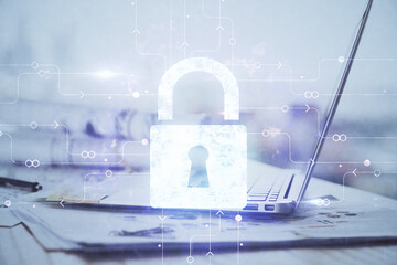 Double exposure of desktop with computer and lock icon hologram. Concept of data safety.