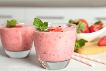 Tasty strawberry smoothie with mint in glass on light grey table