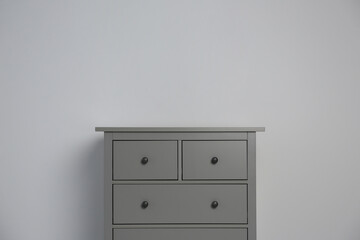 Grey chest of drawers on light background. Space for text
