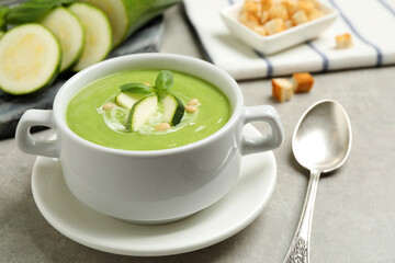 Tasty homemade zucchini cream soup served on grey table