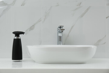Modern automatic soap dispenser near sink in bathroom