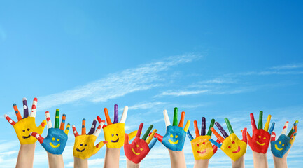 School holidays. Children with painted palms and blue beautiful sky on background, closeup