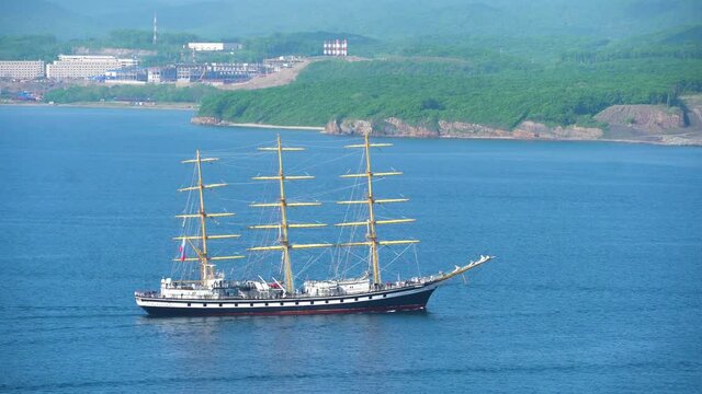 A training sailing ship Pallada passes along the Eastern Bosphorus Strait on the background of the Far Eastern Federal University campus on Russky Island