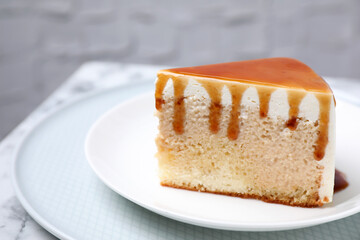 Slice of delicious cake with caramel sauce on table