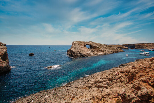 Blue lagoon in Malta. Blue Lagoon greenish-blue water. Cominotto Reef. Turquoise water, reef and sky with clouds.