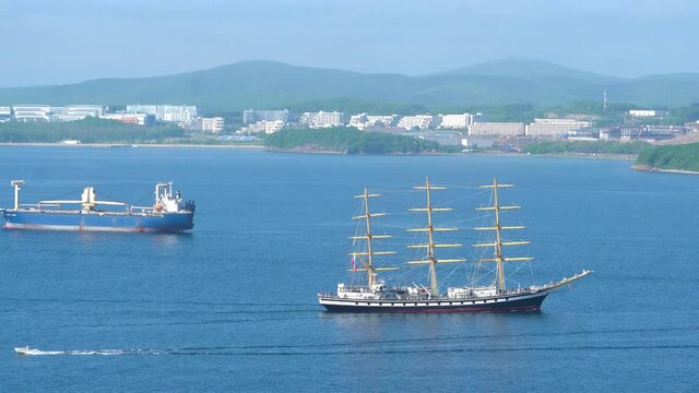 A training sailing ship Pallada passes along the Eastern Bosphorus Strait on the background of the Far Eastern Federal University campus on Russky Island