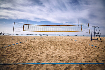 White clouds blue sky golden sand and a volleyball net with the crashing ocean behind on Cabo Verde 