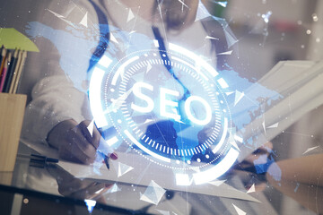 Double exposure of woman's hands making notes with SEO icon. Concept of Search engine optimization