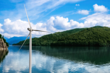 Alternative energy source. Wind turbine near mountains on riverside