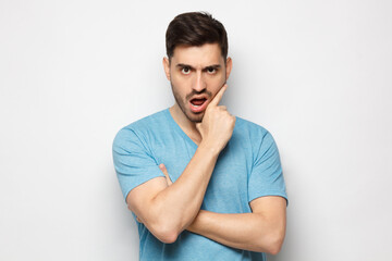 Young man with wtf face, displeased with news, isolated on gray background